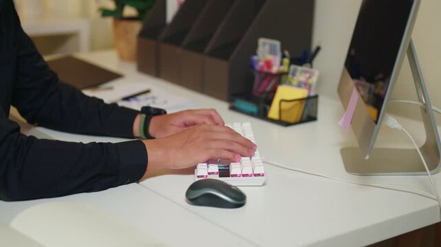 Person Typing on White Mechanical Keyboard at Modern Office Desk with Computer Monitor