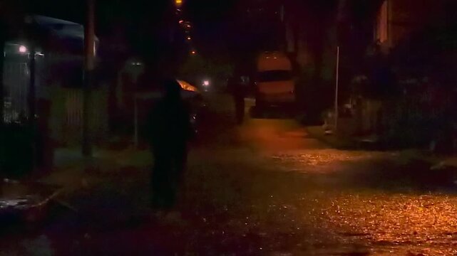 person walking under an umbrella on a rainy night in a small town street