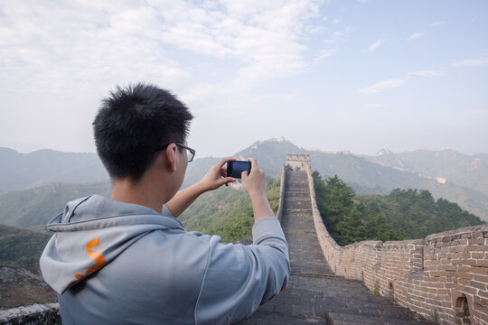 Chinese tourist using smartphone on the Great Wall, Jinshanling, Hebei, China