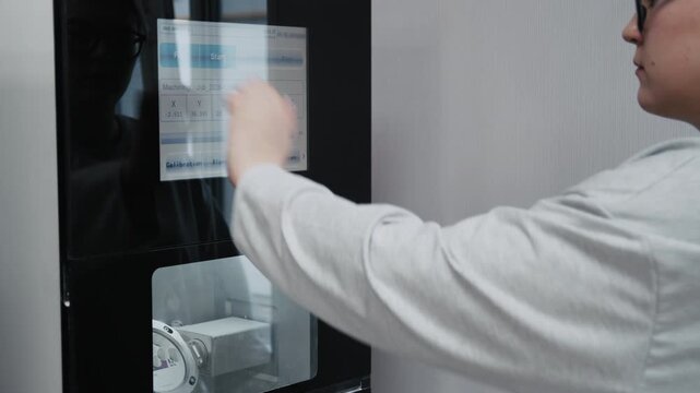 Dental technician operating a modern computer-aided machine in a laboratory workshop