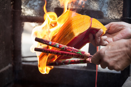 Close-up of hands burning incense sticks during a traditional prayer ritual in a Buddhist temple, Pingyao, China