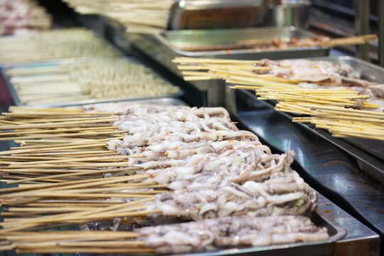 Squid skewers grilling on hot coals at a street food stand, Xi'an, Shaanxi, China
