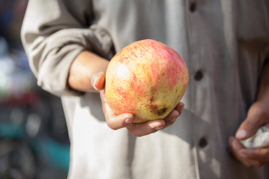 Man presenting a pomegranate in his hand, Xi'an, Shaanxi, China