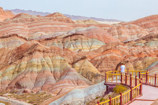Tourist exploring the colorful rock formations of the Linze Danxia landform, Zhangye, Gansu, China