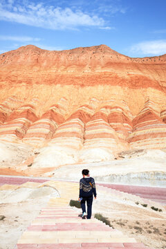 Woman walking into the colorful rock formations of the Danxia landform, Zhangye, Gansu, China