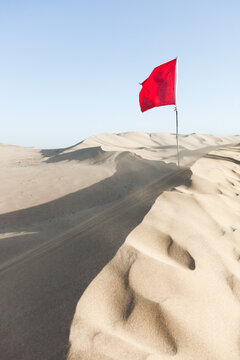 Red Chinese flag on top of Mingsha sand dunes, Dunhuang, Gansu, China