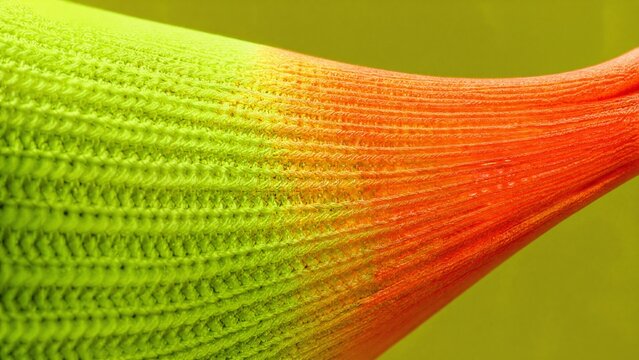 Extreme close-up of stretched fluorescent fabric showing knit structure.