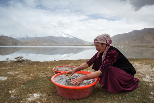 Kyrgyz woman washing wool near the shores of Karakol lake, Karakul, Xinjiang, China