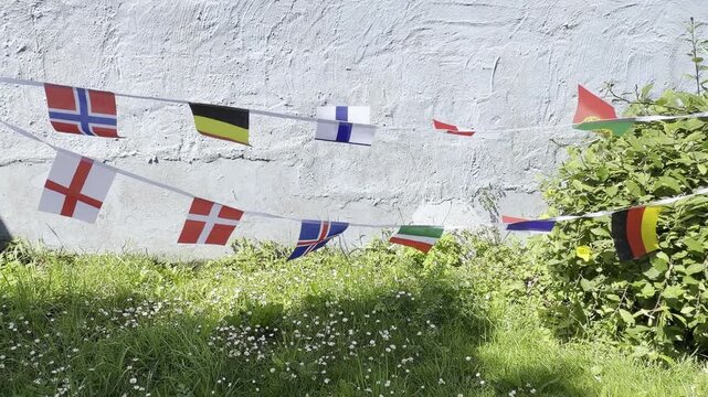 A vibrant display of international flags and decorative bunting fluttering in the breeze. Representing countries from around the world, this colourful scene celebrates unity, culture, diversity, and g