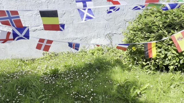 A vibrant display of international flags and decorative bunting fluttering in the breeze. Representing countries from around the world, this colourful scene celebrates unity, culture, diversity, and g