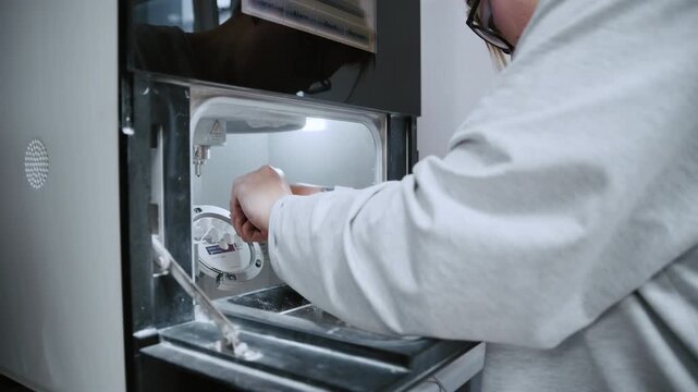 A lab specialist coats a crown pattern with molten wax using a temperature-controlled wax dipper