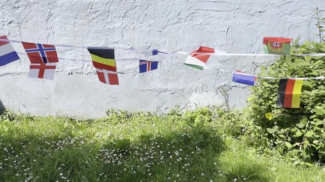A vibrant display of international flags and decorative bunting fluttering in the breeze. Representing countries from around the world, this colourful scene celebrates unity, culture, diversity, and g