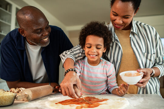 Happy family making homemade pizza together in kitchen