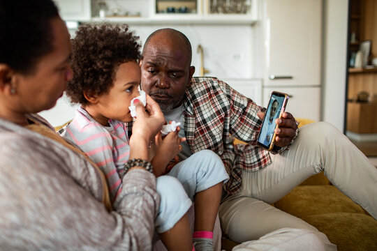 Parents comforting sick child during telehealth consult at home
