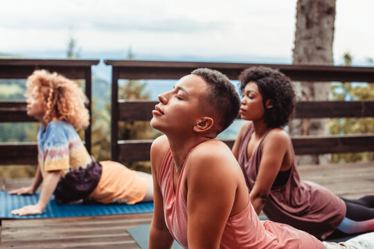 Three women practicing outdoor yoga on mountain deck