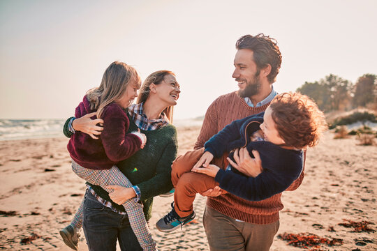 Happy family with two children walking on beach at sunset