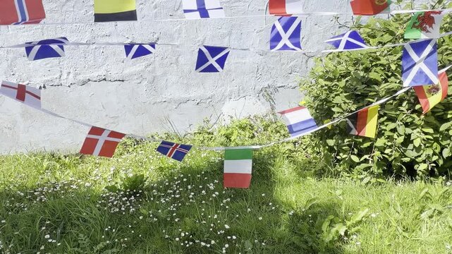 A vibrant display of international flags and decorative bunting fluttering in the breeze. Representing countries from around the world, this colourful scene celebrates unity, culture, diversity, and g