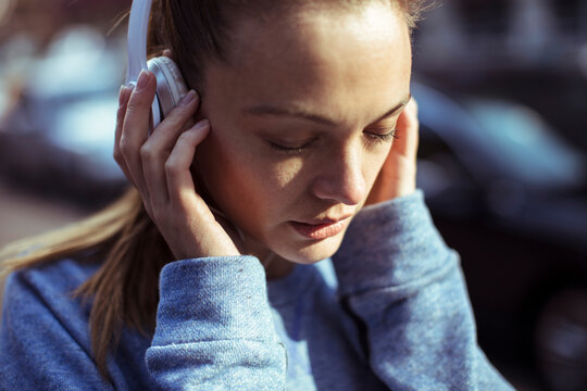 Young woman listening to music on headphones outdoors