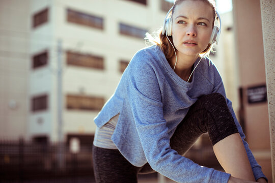 Young woman warming up for a run in the city
