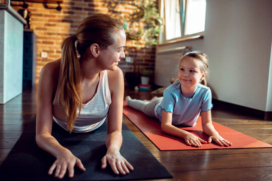 Woman and girl practicing yoga at home