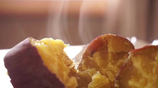 Steaming hot roasted sweet potato, broken open yellow yam with rising steam, delicious warm autumn snack, close up of traditional baked root vegetable
