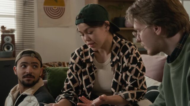 Diverse young students sitting in living room, reviewing bills, Hispanic girl counting cash, and expressing frustration over high household expenses. Personal finance apps or banking advertisements
