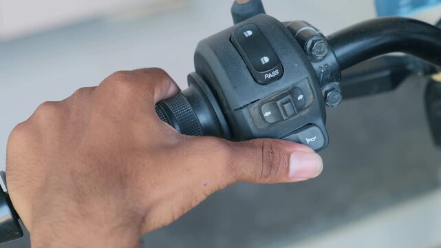 Close-up of a hand pressing the motorcycle horn switch on the handlebar