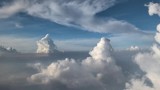 View from an airplane window on a dense layer of white cumulus clouds on a clear day. Travel and freedom atmosphere, daytime flight.