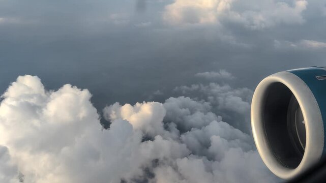 Close-up of an airplane turbine in flight, cumulus clouds, top view. Smooth flight, air travel, tourism.