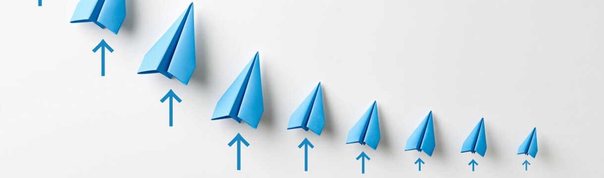 Paper Airplanes in Formation: A line of blue paper airplanes, decreasing in size, ascends with individual upward arrows, symbolizing progress and direction.