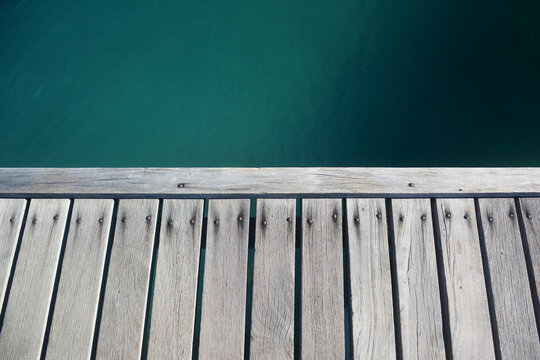 Wooden pier deck over turquoise sea water background.