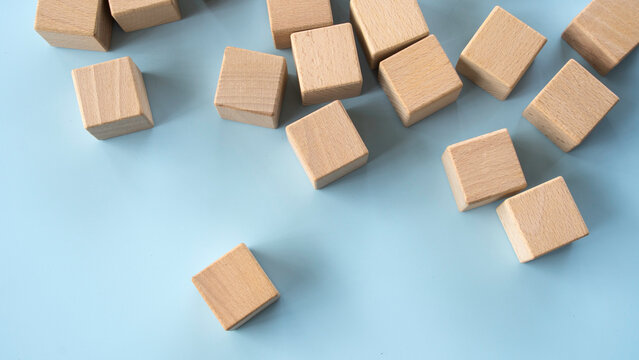 Wooden cubes scattered on a light blue background, emphasizing the concept of construction, building, and design.