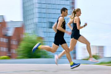 Fototapeta premium Running couple with motion blur in urban fitness training. Concept of speed and motion, performance cardio, running advertising, and dynamic city workout visuals.