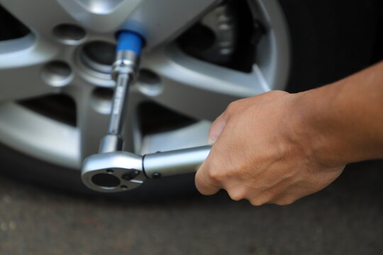 Car Wheel Maintenance with Torque Wrench in Close-Up. A mechanic or car owner using a torque wrench to tighten wheel lug nuts on an alloy wheel during vehicle maintenance.