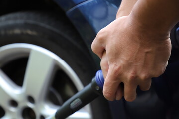 Fototapeta premium Car Wheel Maintenance with Torque Wrench in Close-Up. A mechanic or car owner using a torque wrench to tighten wheel lug nuts on an alloy wheel during vehicle maintenance.