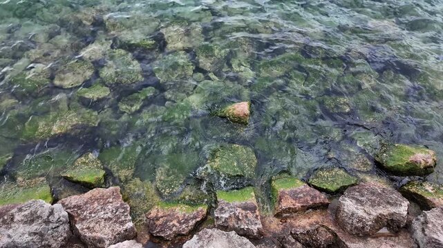 Bardolino, Italy - May 14, 2026 - Clear water flowing over mossy rocks on a sunny day