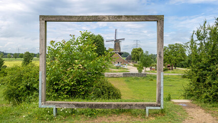 Fototapeta premium Hompesche windmill near Molenplas protected area, seen through an empty frame, in Stevensweert, Limburg, Netherlands
