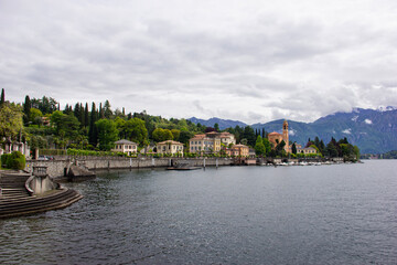 Fototapeta premium Beautiful scenic view of Tremezzo town waterfront on Lake Como, Italy, with traditional alphine villas and mountains under cloudy sky.