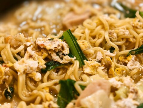 Delicious hot egg noodles cooked in savory broth with scrambled eggs and fresh green vegetables, perfect for Asian food themes.