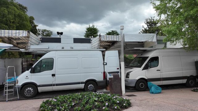 Bardolino, Italy - May 14, 2026 - White delivery vans parked side-by-side with awnings and landscaping