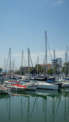 Obraz premium Scenic view of white sailboats and luxury yachts moored in the marina under a clear blue sky on a pleasant summer day