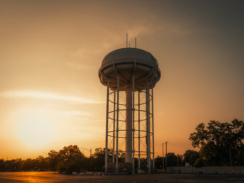 Municipal steel water tower structure standing against a golden sunset sky at dusk in Naperville