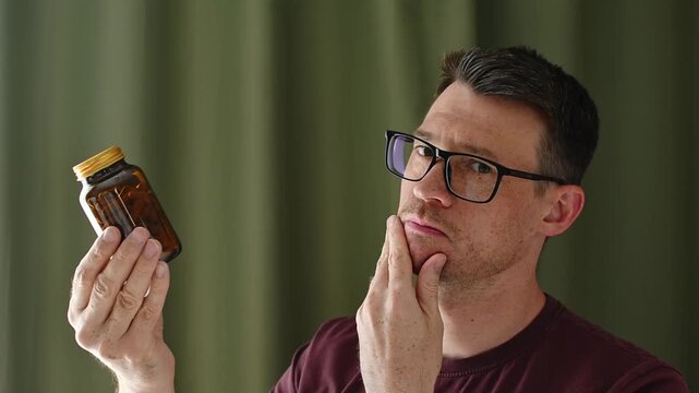 Concerned man studies unlabeled capsule bottle at home and questions supplement safety before treatment decision alone today