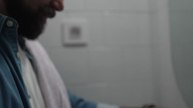 Man applying toothpaste to toothbrush in bathroom