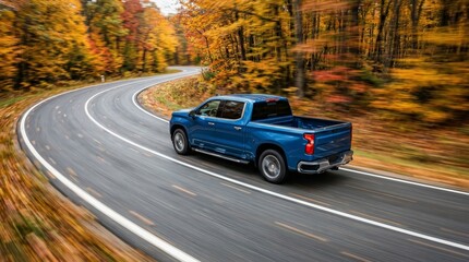 Fototapeta premium Modern blue truck driving along a winding road surrounded by fall foliage.