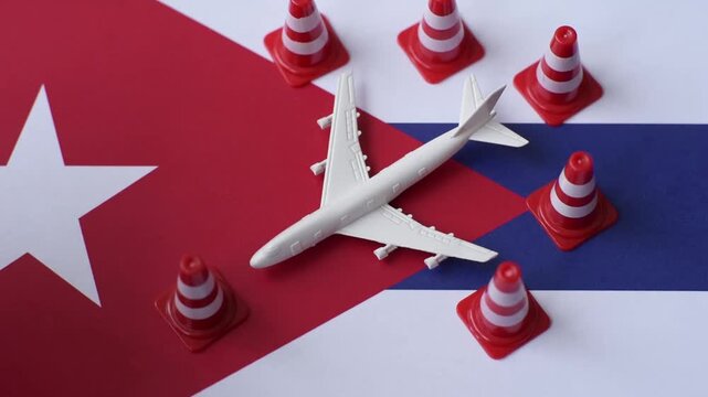 A mock up of airplane surrounded by no fly signs on a Cuba flag as a concept for a flight ban or cancellation