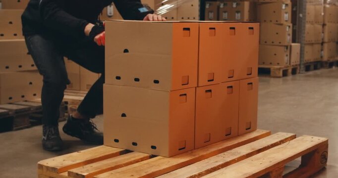 worker in warehouse carries pallets of boxes stacks goods packs. worker in special uniform, worker at work. stages of preparation at factory plant for loading goods for export. Manufacturing big trade