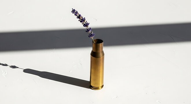 A single dried lavender stem in a spent brass bullet shell on white background with copy space. This conceptual still life is ideal for post-war blogs, websites and pacifism design.
