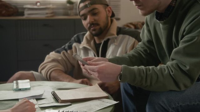 Diverse young adults counting US dollar bills and calculating receits, writing in notebook, Hispanic student offering crumpled dollar bill. Banking, student debt, or personal finance ads
