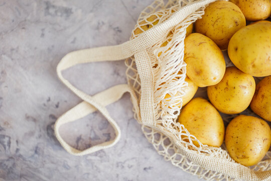 Harvest of fresh golden potatoes nestled in a eco-friendly bag on a rustic kitchen surface